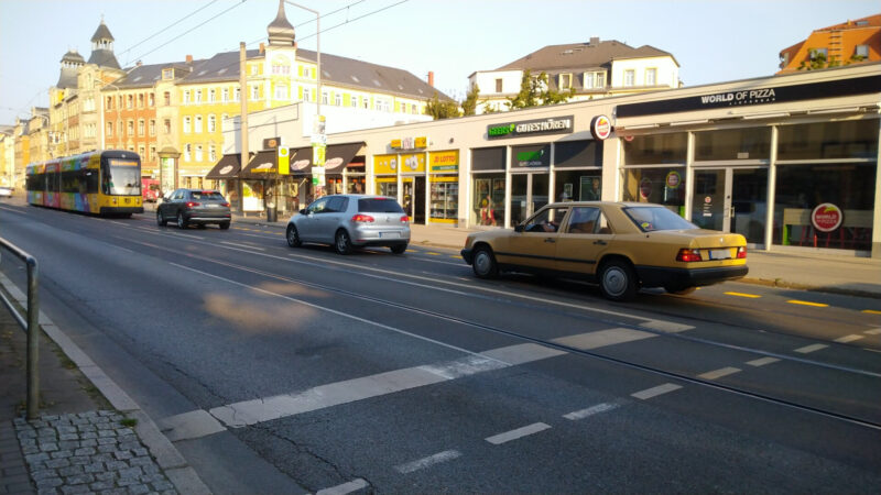 Eine Straßenbahn voraus, drei Autos hinterher im Bereich der Haltestelle Bünaustraße (stadtauswärts). Die Autos fahren auf der Bus-Spur, obwohl hier eine Durchfahrt verboten ist.